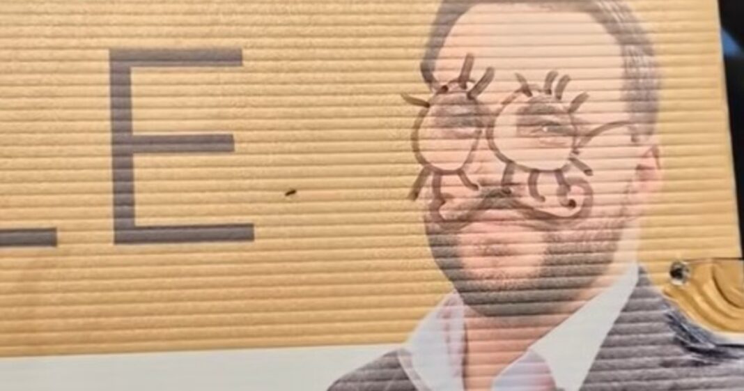 Agente inmobiliario posa junto a su cartel publicitario vandalizado, con su rostro pintado de manera similar.