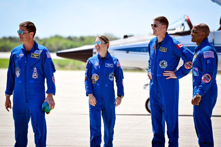 Los cuatro astronautas de la misión Artemis II de la NASA posan frente a un cohete.