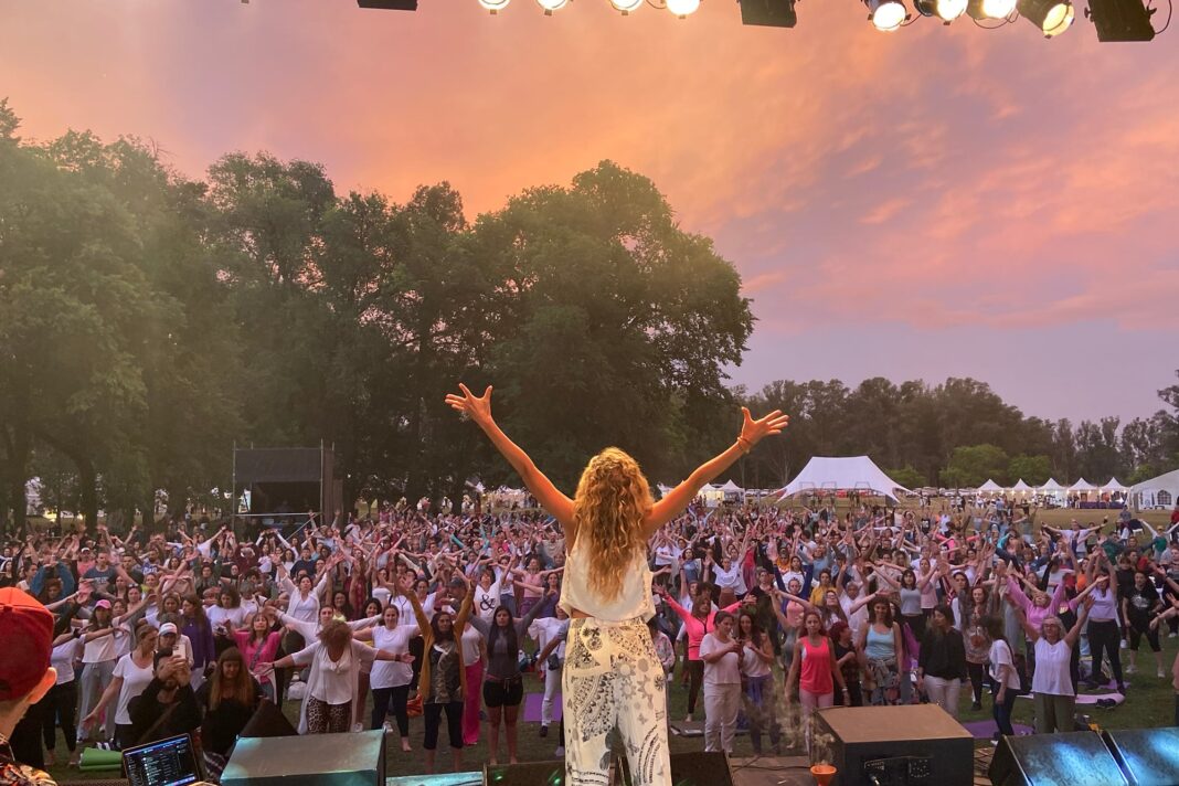 Dafne Schilling dirigiendo una sesión de baile y bienestar grupal en un evento.
