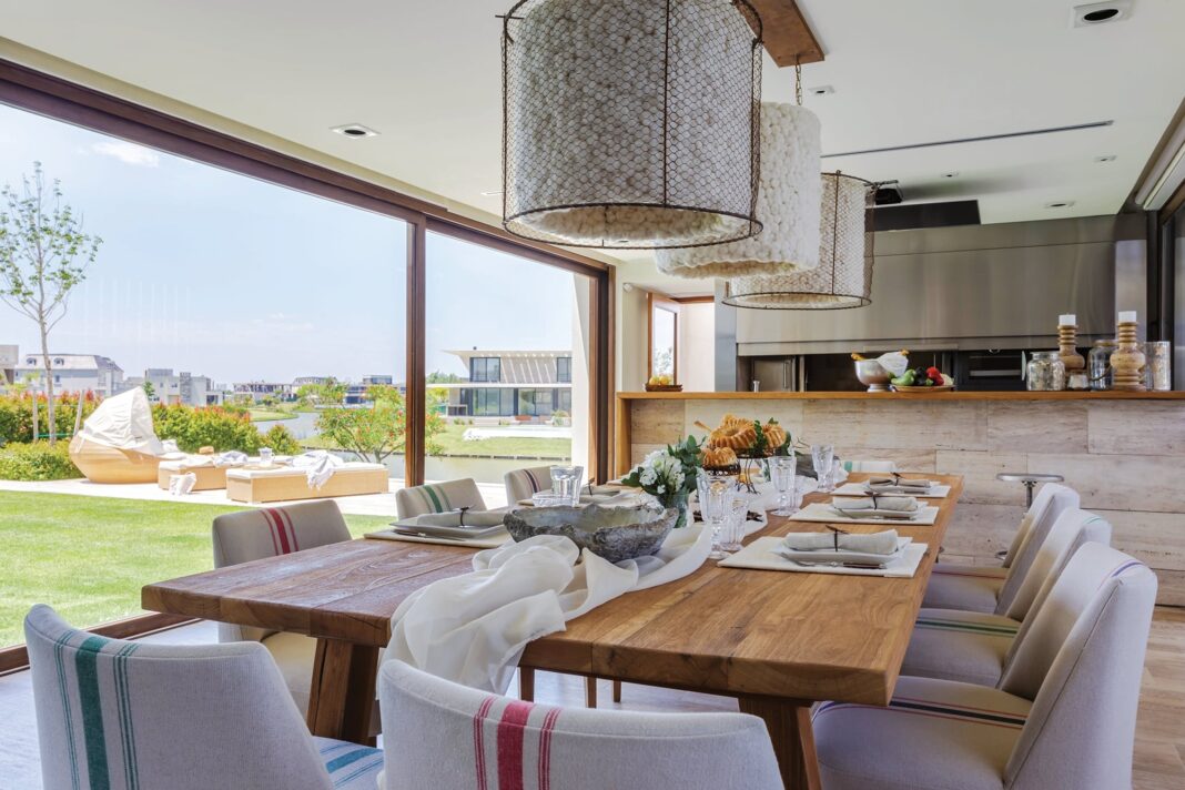 Quincho moderno con parrilla, integrado en el jardín de una casa, con mobiliario exterior.