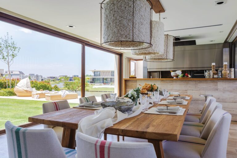 Quincho moderno con parrilla, integrado en el jardín de una casa, con mobiliario exterior.