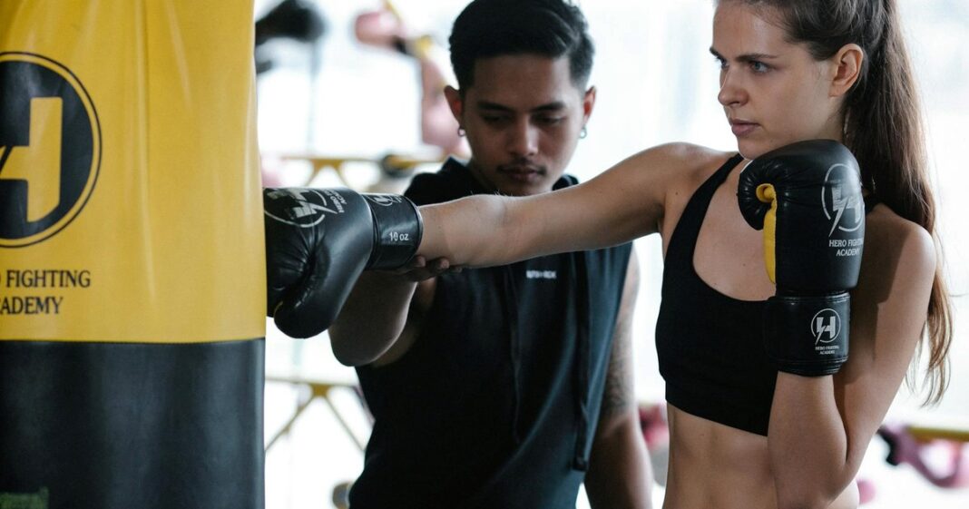 Persona mayor realizando ejercicios de fuerza con mancuernas en un gimnasio, sonriendo.