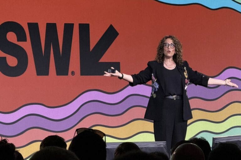 Futurista Amy Webb hablando en un escenario sobre tendencias y cambio, con gráficos de evolución de fondo.
