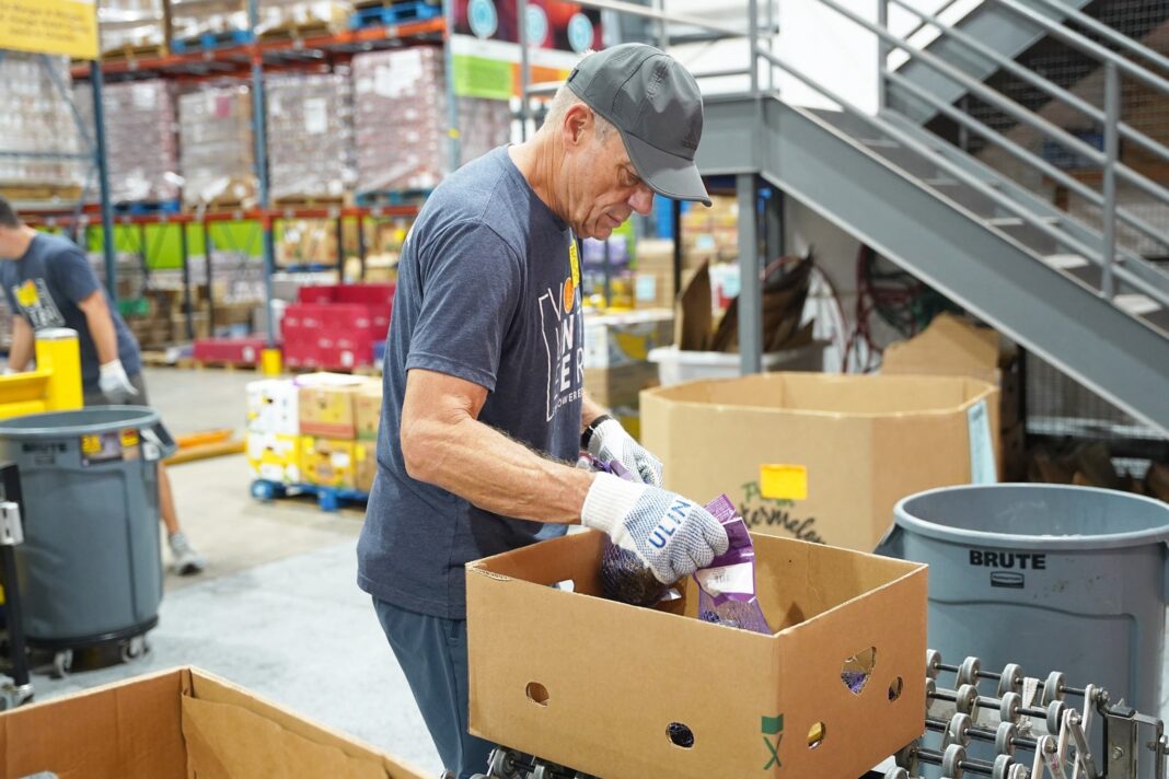 Trabajador agrícola en un campo con cajas de alimentos de ayuda social