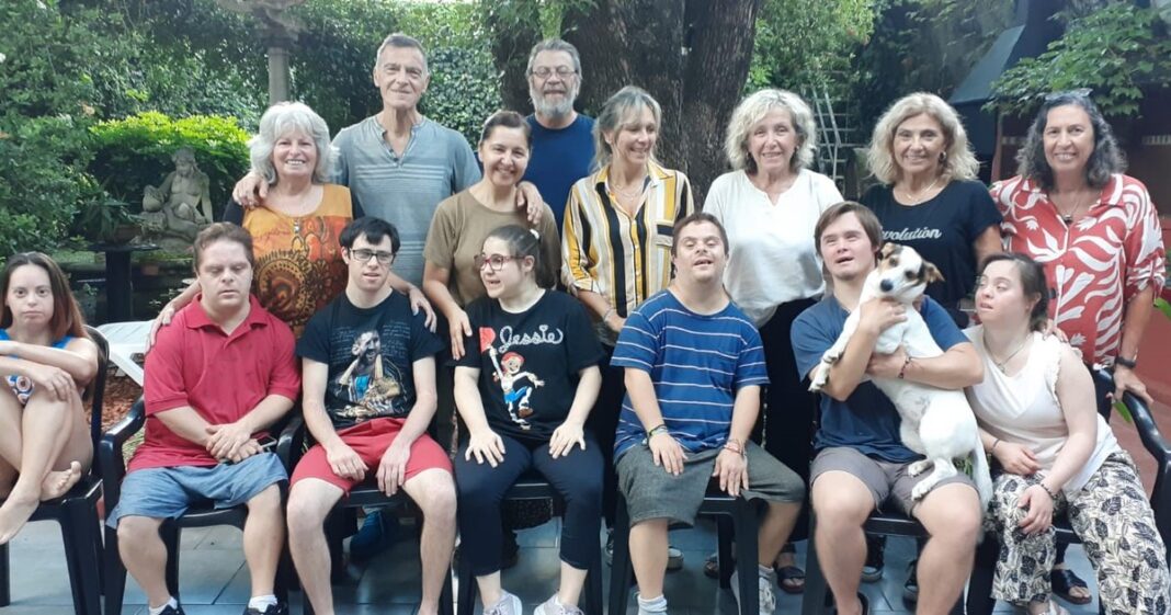 Ilustración de un grupo de personas conversando frente a un edificio de departamentos, representando el concepto de vivienda en comunidad.