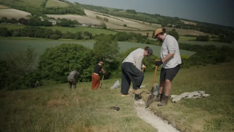 Voluntarios colocando tiza fresca en el contorno del Gigante de Cerne Abbas en una colina del sur de Inglaterra