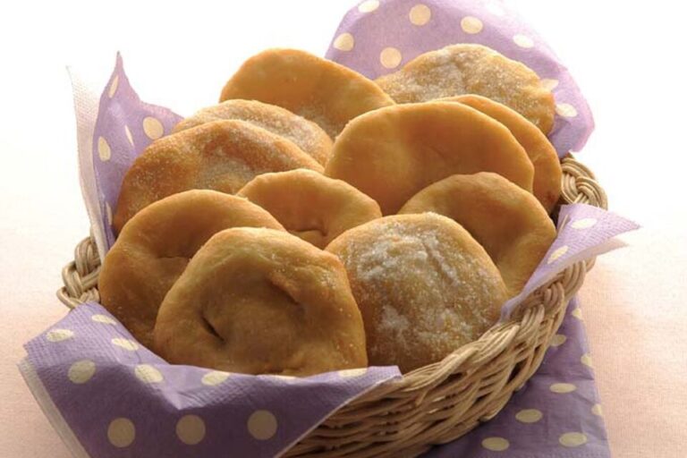 Tortas fritas criollas recién hechas, espolvoreadas con azúcar, sobre un plato