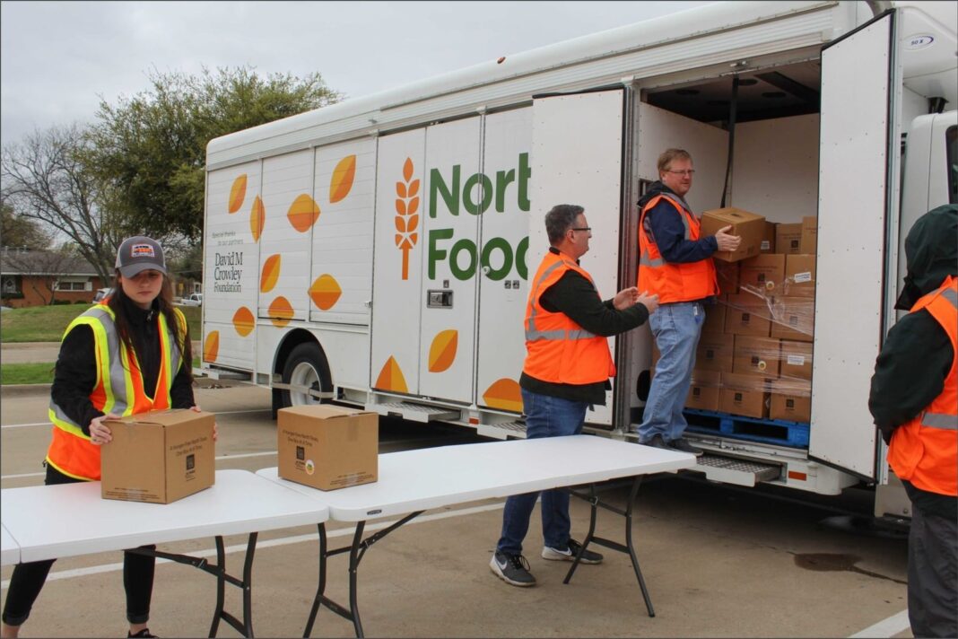 Personas recibiendo cajas de alimentos frescos en una despensa comunitaria en Texas