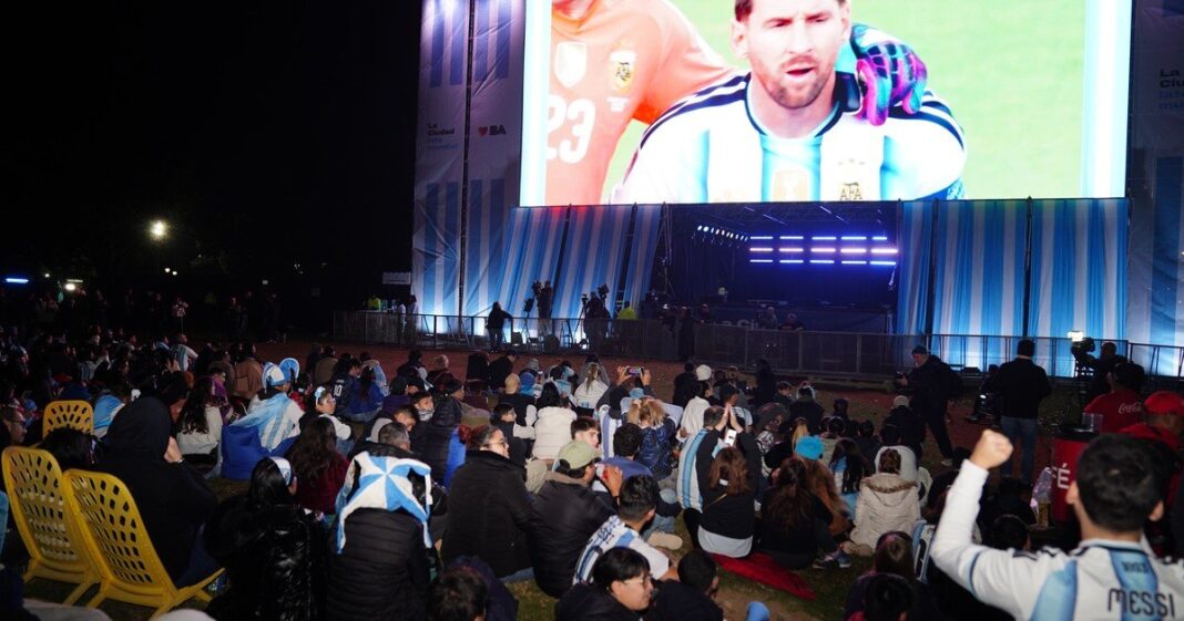 Pantalla gigante en espacio público con hinchas argentinos viendo un partido de fútbol