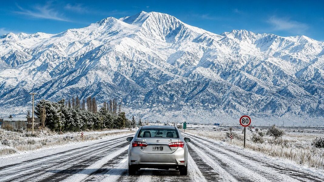 Auto circulando sobre una ruta nevada en la cordillera argentina