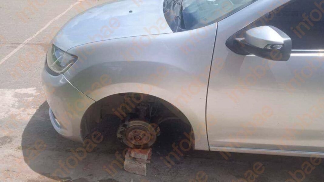 Auto estacionado con las ruedas traseras y delantera faltantes, apoyado sobre ladrillos