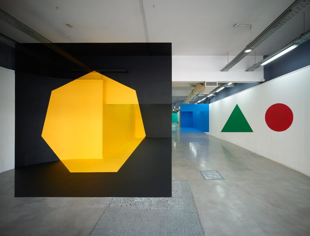 Sala de exposición con fotografías de gran formato y figuras geométricas pintadas en paredes